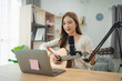 © WMSTUDIO - Young woman sings and plays guitar in a modern home studio, showcasing her talent during an online live performance with a laptop and microphone setup.