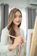 © WMSTUDIO - Young woman painting on canvas in bright indoor space, focusing on artwork with a joyful expression, creative hobby and artistic journey captured beautifully