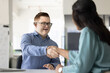 © fizkes - Female business professional giving handshake to male employee