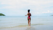 © kelvn - Beautiful African american woman in pink bikini on tropical beach. Portrait of dark skinned woman smiling at sea. Brunette tanned girl in swimwear enjoying and walking on beach.