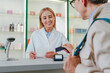 © Westend61 - Pharmacist assisting customer with credit card payment at pharmacy counter