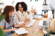 © Studio Marmellata - Two young women collaborate at a desk, discussing ideas while looking at a tablet and notebook.