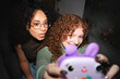 © Studio Marmellata - Two young women with curly hair take a selfie with a purple toy camera, one sticking her tongue out playfully.