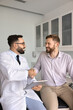 © fizkes - Satisfied man patient shaking hands with smiling professional therapist