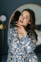 woman wearing pajamas posing in elegant bedroom with blue walls