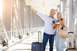 © Anastasiya - Smiling senior man with wife pointing at copy space at airport