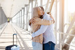 © Anastasiya - Mature couple hugging at airport corridor with suitcase nearby, enjoying reunion