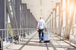 © Anastasiya - Senior man walking away in airport corridor pulling suitcase, holding passport