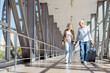 © Anastasiya - Happy senior couple walking at airport corridor with luggage, holding hands