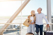 © Anastasiya - Happy mature couple hugging at airport window with suitcases beside them