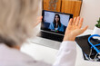 © Xavier Lorenzo - Mature female doctor consulting young patient via virtual video call visit using laptop computer. Digital online healthcare, distance telemedicine. Telehealth videocall. Over shoulder view