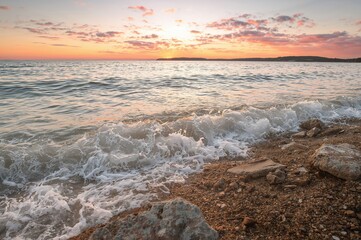 Wall Mural - Sunset Over the Water's Edge, Shimmering Waves Hitting the Rocks, Golden Light Glimmering