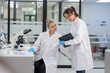 © Freeday photo - Two scientists in white lab coats collaborate on research in a modern laboratory setting during daylight hours