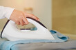 © JK_kyoto - Close-Up of Hand Using Steam Iron on Wrinkled Fabric for Home Laundry Task and Garment Care in Modern Interior Setting