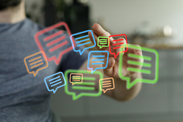 A man interacts with speech bubbles, symbolizing digital communication, connectivity and social media interaction. Conceptual shot for technolog