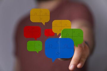 Conceptual shot of a man pointing to puzzle speech bubbles representing connection, communication, and brainstorming sessions.
