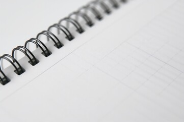 Wall Mural - Close-up of a spiral-bound notebook showing lined pages for writing and note-taking in an office or educational setting