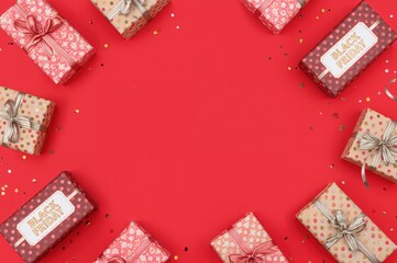 Wall Mural - Gift boxes and shopping bags with tags on a red backdrop. Black Friday discount event. Aerial perspective