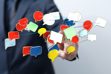 Conceptual image of a man interacting with colorful speech bubbles representing social media or online communication. Illustrating connection an