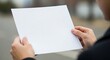 © Octopus16 - Person Holding Blank White Paper in Outdoor Setting