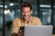 © Space Priest - Smiling caucasian male in office using smartphone and laptop