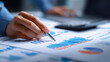 © kaliel - Hand analyzing business charts with a pen on printed reports, symbolizing financial analysis decision making and the concept of evidence based strategy and performance management.