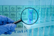 © New Africa - Scientist holding magnifying glass against test tube with DNA spiral inside in laboratory, closeup. Genetic analysis and research