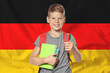 © New Africa - Little boy with backpack and stationery against flag of Germany. Language school