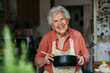 © Halfpoint - Happy senior woman cooking at home.