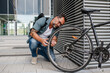 © Halfpoint - Man fixing bicycle wheel outdoors.