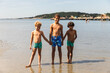 © Diego Martin/Stocksy - Three Siblings Standing on the Beach