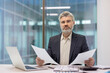 © Liubomir - Senior businessman reviewing documents in modern office