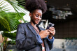 © Jovo Jovanovic/Stocksy - Woman in blazer smiles while using her phone.