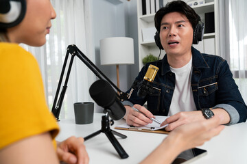 Smiling radio influencer host wearing headphone interviewing woman speaker sharing information to listeners on social media online website live streaming channel at morning at studio record. Infobahn.