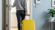 © Meow Creations - Woman in grey sweater and dark jeans pulling a yellow suitcase, opening a door, ready for travel