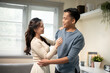 © bongkarn - Sweet couple asian man and woman holding hugging each other while standing in a living room at home