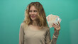 © Krakenimages.com - Woman enjoying money while smiling in british campaign shows blonde young investor holding cash and pound notes on studio green background.