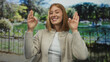 © Krakenimages.com - Young woman smiling in a sunny park displaying her fingers in an okay gesture reflecting joy and outdoor freedom among lush greenery and a peaceful atmosphere