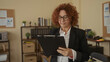 © Krakenimages.com - Woman reviewing clipboard in modern office surrounded by documents, shelves, charts, and professional environment showcasing business and organization