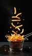 © Vadym - Golden fries spill out of metal basket. French fries jump out of frying basket on black background. Crispy potato sticks fly through air, some crumbs fall on dark table.