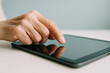 © Aleksandra - Close up of adult hand using digital tablet touchscreen for browsing, selecting apps, or reading online content