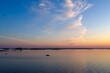 © Tommy - Calm lake with distant forest and pastel sky at sunset