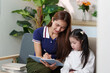 © itchaznong - Learning Together: Mother Writing While Daughter Observes