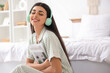 © Pixel-Shot - Beautiful young woman with modern headphones and magazine listening to music on floor in bedroom