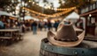 © AndiAzis - Close-up of a cowboy hat resting on a barrel at an outdoor festival with blurred crowd