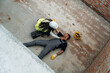 © standret - Top view. Man, construction worker fell from big height, lying down without consciousness, accident, woman is checking