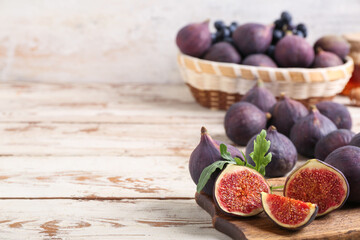 Wall Mural - Cutting board with fresh ripe figs and arugula on white wooden background, closeup