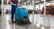 © rdkcho - Worker operating a large floor cleaning machine in a bright industrial facility.