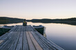 © Pascal Huot - Québec, Canada. Une femme seule se détend au bout du quai. Lever de soleil sur le lac en forêt.