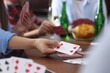 © New Africa - Friends playing cards at wooden table indoors, selective focus